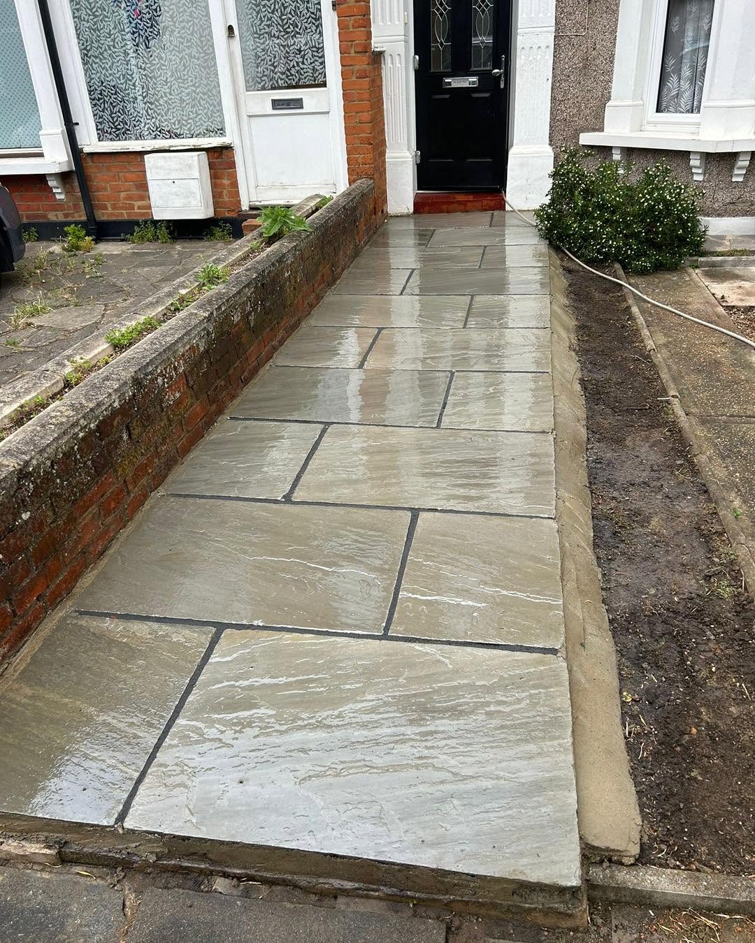 Finished Indian sandstone patio with crisp pointing and brick border